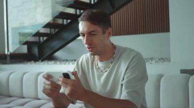 Millennial 'daki adam, zaferin olumlu duygularla kazanılması üzerine akıllı telefondan online oyun oynuyor. Beyaz erkek akıllı telefon ifadesinde online oyun oynuyor zafer ve gurur yayıyor