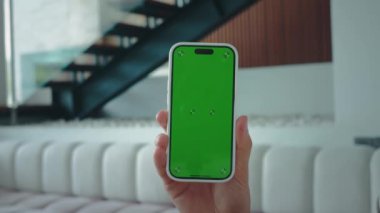 Yeşil renkli ekranlı akıllı telefonu tutan insan eli dijital ortamda yeşil ekranların rolünü vurguluyor. İçerik oluşturmada yeşil krom ekran teknolojili akıllı telefon