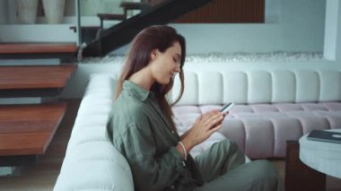 Uzaktan iletişim kuran kadın koltukta dinlenirken uzaktan telefon mesajı atıyor. Beyaz kadın koltukta otururken arkadaşlarıyla telefonda canlı mesajlaşır.