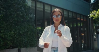 Kendine güvenen güzel bir kadının ışıltılı gülümsemesi kollarını kavuşturdu ve mutlu oldu. Gülümseme dünyayı aydınlatır. Genç yetişkin kadın sakin ve mutluluk saçar. Anın zahmetsiz güzelliğini somutlaştırır.