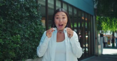 Pozitif kadın gözlüğünü çıkarır. Yüzü mutluluk ve mutlulukla parlar. Önünde gördüğünden memnun olur. Dişi, geniş bir gülümsemeyle gözlüğü çıkarıyor. Yüzünde zevk ve heyecan dolu bir ifade var.