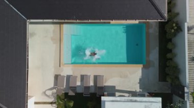 Üst düzey bir adam dinlenirken büyük bir yüzme havuzuna takla atıyor. Erkek, lüks bir tatil köyünde yaz tatilinin tadını çıkarırken havuza dalıyor ve orada yüzüyor. Aktif yaz tatili konsepti