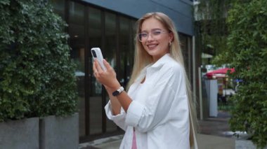 Başarılı blogcu akıllı telefonu tutuyor içerik yaratıyor, popüler blogcu açık havada gülümsüyor, etkili blogcu neşeli anı paylaşıyor, sosyal medya için ideal, teknoloji görselleri