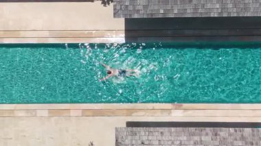 İnsansız hava aracı, özel villa havuzuyla rahatlamış turistleri yakalıyor, turistler güneşlenirken eğleniyor, turistler tropik atmosferleri kucaklıyor, dünya çapında tatil pazarlama için mükemmel.