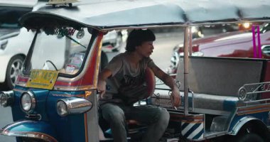 Bangkok, Tayland - 05 Mayıs 2024: Man Asian tuk sürücüsü turistleri, yolcuları, şehrin dört bir yanında taşıdı, sürücü Bangkok şehrini durdurdu. Tayland 'da toplu taşıma aracı, Tuk tuk taksi şoförü gezintiye çıkıyor.