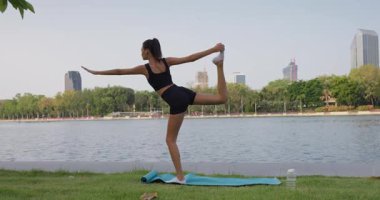 Huzurlu Park Gölü 'nün yanında yoga pozisyonunda ustalaşan kadın, her akışkan hareketi dengeleyen denge, düşünceli egzersizi geliştiren denge, dünya çapında sağlık ve sağlıklı yaşam tarzı kampanyaları için mükemmel..