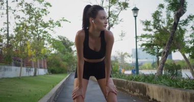 Güçlü, yoğun bir doğa egzersizinden sonra iyileşen bir kadın, sakin bir mahallede fitness inadını vurguluyor. Sporcu, motivasyon kampanyaları için uygun olan sağlıklı günlük rutini kucaklıyor.