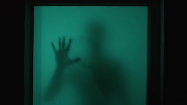 Korku sahnesi: Psikopat silueti pencerenin diğer tarafında uğursuz bir şekilde cama dokunuyor, bakıyor, korkunç bir şekilde çığlık atıyor. Kâbus gibi korkunç psikopat gece seni pencereden izliyor. Korku konsepti