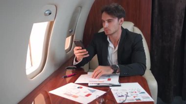 Uçaktaki iş adamı telefondaki ortaklara mesaj yazarak birçok belgeyi çevreledi. Adam telefondaki verilerle belgeleri inceliyor. Uzman, uçuş sırasında belgeleri düzenlemeye karar verdi.