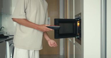 Yemek için mikrodalga kullanan adam, modern mutfakta kolaylık sağlayan mikrodalga fırın, hızlı yemek sağlayan mikrodalga fırın, dünya çapında günlük yemek ve yaşam tarzı projeleri için ideal içerik