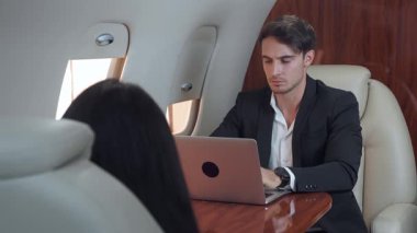 Çekici adam dizüstü bilgisayarında uçakta iş arkadaşının yanında yazıyor. İş adamı uçakta uçarken bütün işleri bitirmeye çalışıyor. Uçak penceresinden görünüm işten uzaklaşmaz