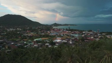 Tropikal cennet adasının okyanusu üzerinde gökkuşağı. Palmiye ağaçları, akşam sineması çekimleri. Gökkuşağı denizin ve dağların üzerinde. Tropikal fırtınalı bulutlu gökkuşağı üstüne yağmur yağar.