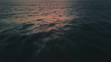 Koyu mavi okyanus suyu çarpıcı günbatımından canlı pembe ve turuncu renkleri yansıtır. Hafif bulanık uzun pozlarda yakalanır. Huzurlu manzara havasını arttırır. Altın sabah ışığında hafif dalgalanmalar