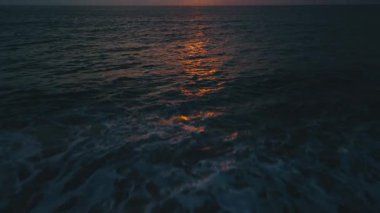 Okyanus yüzeyi ilk ışıkla parlıyor. Alacakaranlıkta karanlık okyanus dalgalarına yansıyan altın gün batımı ışığı çarpıcı ve sakin doğal bir zemin oluşturarak huzur dolu düşünceleri davet ediyor.