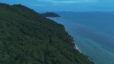 Orman sırtı denize iniyor. Bereketli yeşil tropikal orman sarp yamaçları kaplıyor. Alacakaranlıkta el değmemiş beyaz kum plajı ve kristal berrak turkuaz okyanus suyuyla buluşup huzur yaratıyor.