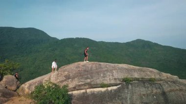 Dev uçurum platosunu keşfeden arkadaşlar. Turistler dağların tepesinde büyük bir kaya formasyonunda yürürken, yemyeşil dağların nefes kesen manzaraları, macera ve keşif ruhunu somutlaştırıyor..