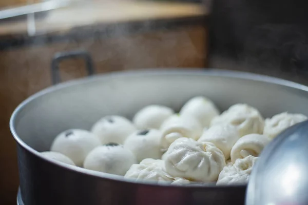 a stuffed steamed bun in a pot of steam boiler in the streets food, this is famous Chinese food with various tastes.