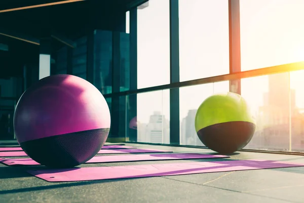 a fitness center and a healthy concept Yoga ball and exercise mat on a wooden floor with a sky-blue backdrop.