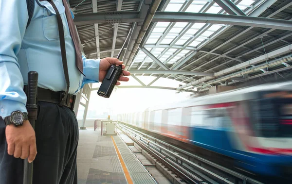 Elektrikli tren istasyonunda telsiz tutan profesyonel güvenlik görevlisi.