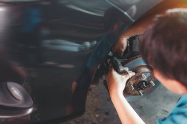 Garaj arabaları için yepyeni fren diskleri. Otomobil teknisyeni garajda yeni lastikleri değiştirip frenleri tamir etmeye çalışıyor..