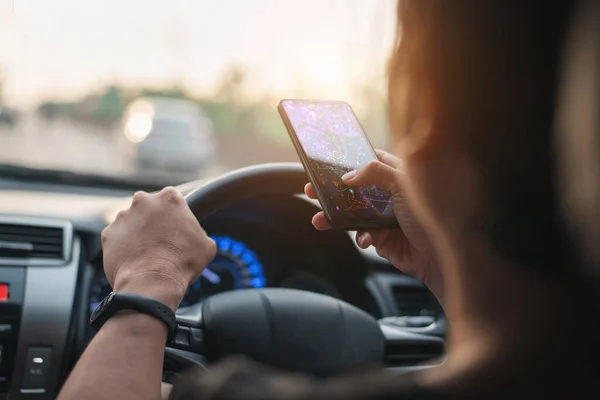 一辆黑色汽车的女司机在你的智能手机上查一下你的路线图 并使用应用程序到那里旅行 它位于一个州际公路上 — 图库照片