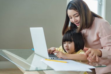 Neşeli bir anne ve çocuk ev ödevlerini tamamlamak için bilgisayarlarını kullanıyorlar. Aynı zamanda oyun ve ilginç haberler arıyorlar. Sarışın çocuk internette bir şeyler arıyor.