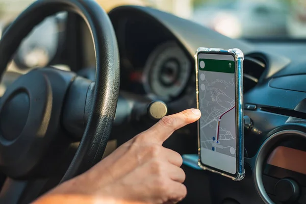 男人开车的时候 用他的智能手机上的绘图应用程序找到他的位置 用电话作为汽车上的导航装置 — 图库照片