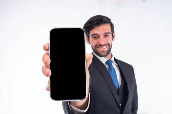モバイルアプリケーション広告 ハンサムでアニメーションの男が白いスタジオの背景の前にポーズし 空のスマートフォン画面を指差し カメラで笑う — ストック写真