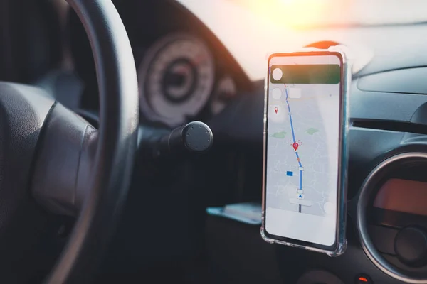 The phone\'s map appears on the dashboard and street in the background. White cell phone mounted in a mounting with GPS navigation and a map. duplicate the space.
