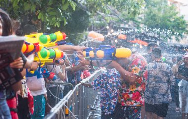 Kalabalık, güneşli bir yaz festivalinde neşeli bir su tabancası savaşının keyfini çıkarıyor.