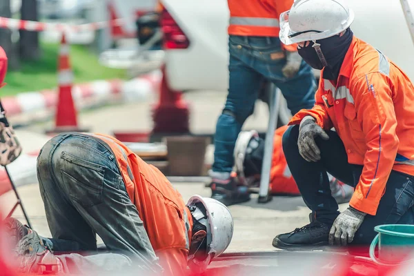 Güvenlik teçhizatı tamir eden bir grup teknisyen, yoğun bir benzin istasyonundaki alt kattaki yakıt deposunu onarıp operasyon güvenliğini sağlıyorlar.
