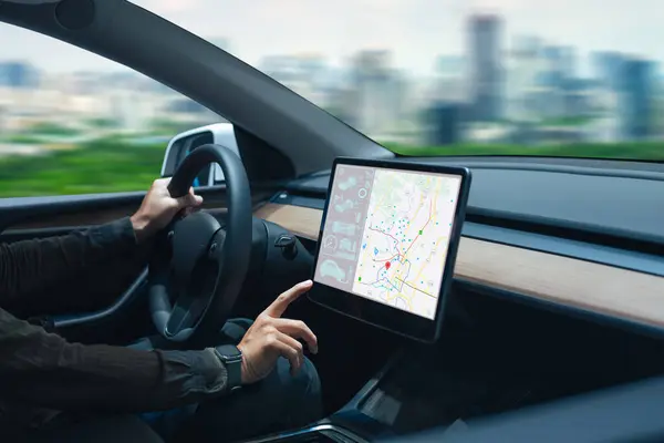 Person driving a car while interacting with a modern touchscreen navigation map in the dashboard