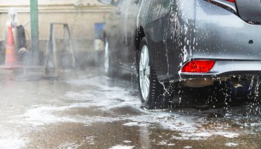 Araba yıkama istasyonunda su ve sabunla iyice temizlenen bir sedan.