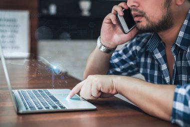 Telefonda konuşan ve dijital güvenlik arayüzü olan bilgisayar kullanan bir adam uzaktan çalışmayı ve siber güvenliği gösteriyor..