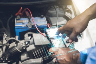 Tamirci, bir arabanın aküsünü ve elektrik sistemini garajda sorun var mı diye kontrol etmek için bir teşhis aracı kullanır..