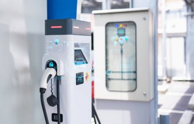 Modern teknolojiyi vurgulayarak, gelişmiş dijital arayüzü ve holografik görüntüsü olan bir elektrikli araba şarj istasyonunun yakın çekimi.