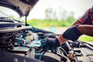 Fütürist dijital simgelerle donatılmış bir araba motorunu tamir etmek için İngiliz anahtarı kullanan bir tamircinin eldivenli ellerine yakın çekim.