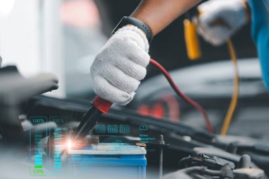 Tamirci eldiven giyerek elektrikli araba aküsünü tanısal verilerle dolduruyor, otomotiv onarımı ve bakımını vurguluyor.