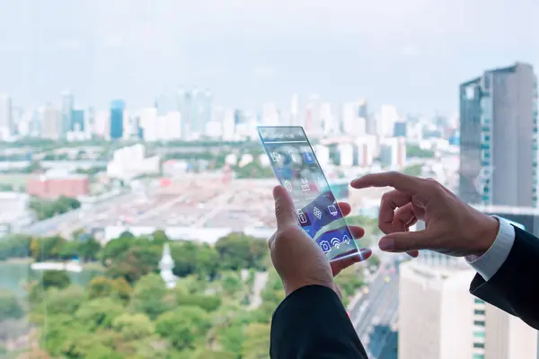 stock image Businessman using futuristic smart home control interface with a cityscape view in the background, highlighting modern technology.