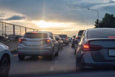 Gün batımında şehir otobanında trafiğe takılan arabalar, bulutlu bir gökyüzünün altında parlayan fren lambaları karamsar bir atmosfer yaratıyor..