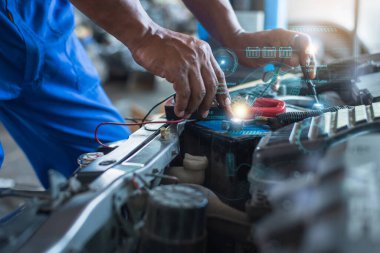 Teknik ayrıntıları gösteren dijital arayüz örtülü elektrikli araba aküsü üzerinde çalışan bir tamircinin ellerinin yakın çekimi.