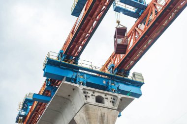 Köprü inşaatı sırasında ağır vinç kaldırma ekipmanlarının yakın çekimi, endüstriyel mühendislik ve altyapı geliştirme sergileniyor.
