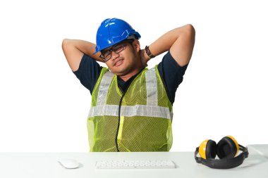 Güvenlik yeleği ve kasketli bir inşaat işçisi masada uzanıyor ve dinleniyor, yorgunluk ve iş stresi gösteriyor..