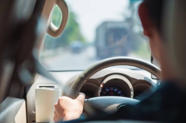 Önünde bulanık bir yol ve kamyon olan bir arabanın içinde direksiyonu tutan bir sürücünün yakın çekimi..  