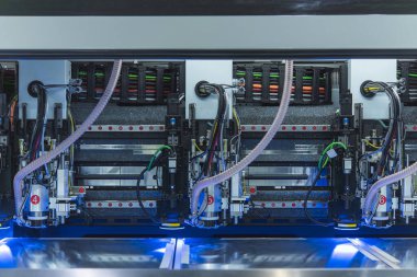 Mavi LED aydınlatma altında çalışan gelişmiş bir sanayi CNC makinesinin robot otomasyonu, kabloları ve hassas bileşenleri ile yakın plan görüntüsü.