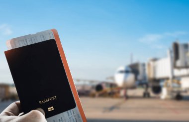 Pasaport ve uçuş kartı taşıyan yolcu uçak arka planda, hava yolculuğunu, turizmi ve uluslararası yolculuğu temsil ediyor..