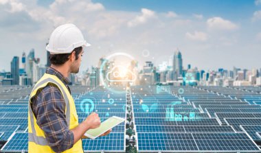 Sert şapka ve güvenlik yeleği giyen erkek mühendis, dijital enerji verileriyle güneş panellerini izlemek için bir tablet kullanıyor..