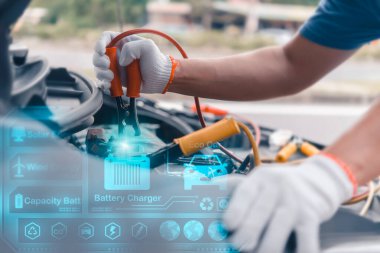 Eldiven giyen tamirci, akü kablolarını gelecekteki dijital arayüz görüntüleriyle birlikte elektrikli araba aküsüne bağlıyor.