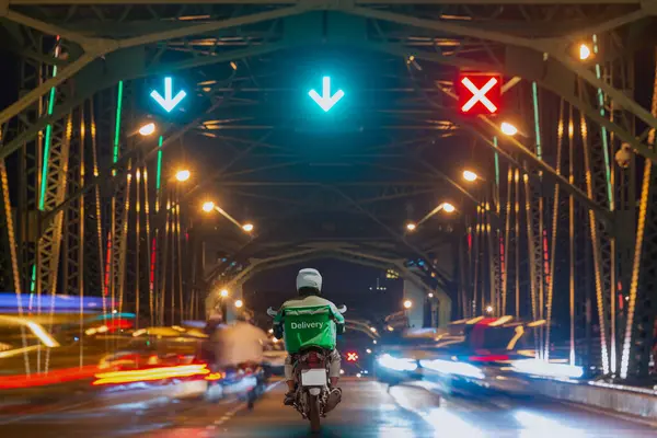 Scooter 'da yemek dağıtımı yapan sürücü gece aydınlatma köprüsü ve trafik işaretleriyle aydınlandı..