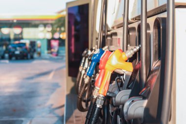 Gündüz vakti modern bir benzin istasyonunda sıralanmış renkli yakıt pompası başlıkları yakıt seçeneklerini ve enerji tüketimini sembolize ediyor..